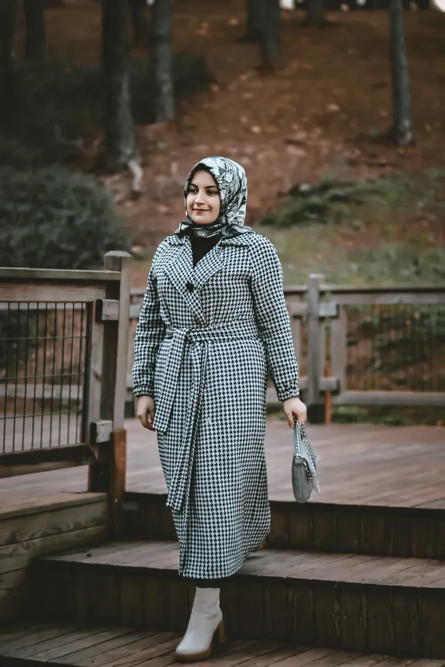 Kazayağı desenli kuşaklı uzun kaban giyen kadın, ahşap merdivende